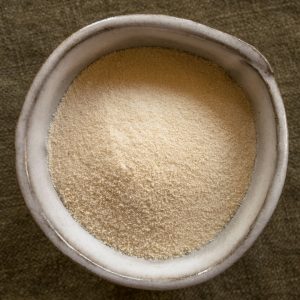 En liten skål med agar-agar-pulver, fint pulver i ljusfärg, för geléer och desserter.