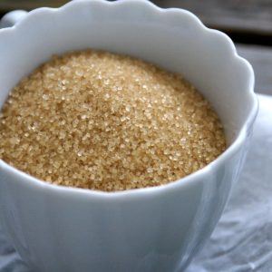 En liten vit skål med fylligt brunt socker i kristaller, redo för bakning eller desserter.