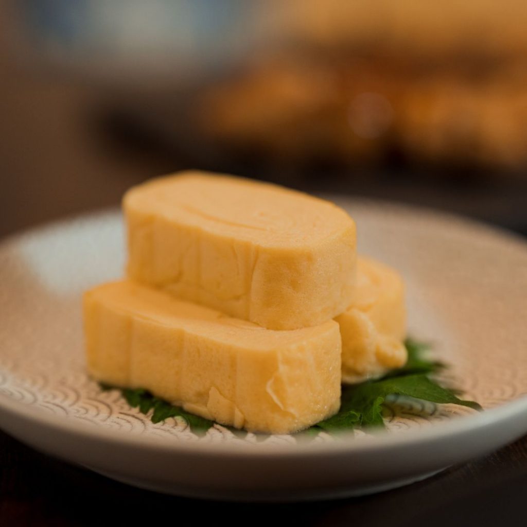 En rullad japansk omelett, i gyllene gul rullad till en slät och krämig block, med söt och salt smak.