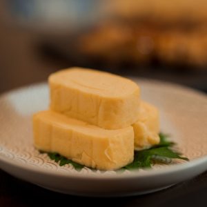 En rullad japansk omelett, i gyllene gul rullad till en slät och krämig block, med söt och salt smak.