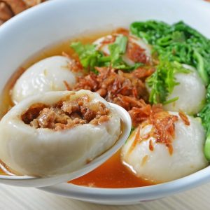 En skål med Salta tang yuan med köttfyllning i en klar buljong med grönsaker och sesamolja