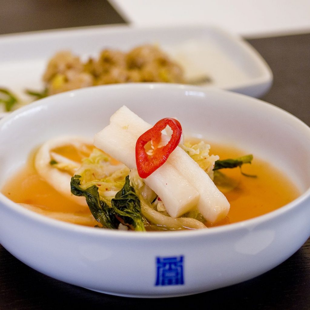 En skål med koreansk dongchimi, en lätt och uppfriskande rätt av vit kimchi i kyld radisksoppa.