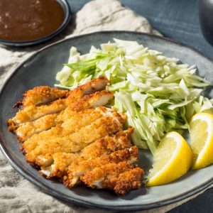 En tallrik med Knapriga kyckling katsu-skivor serverade med tonkatsu-sås och strimlad vitkål vid sidan