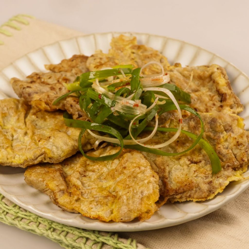 En tallrik med yukjeon, tunna skivor kött täckta med äggsmet och stekta gyllene.