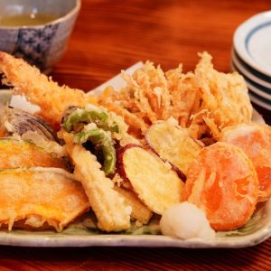 Ett fat med gyllenebrun friterade och frasiga tempura med räkor, sötpotatis och grönsaker