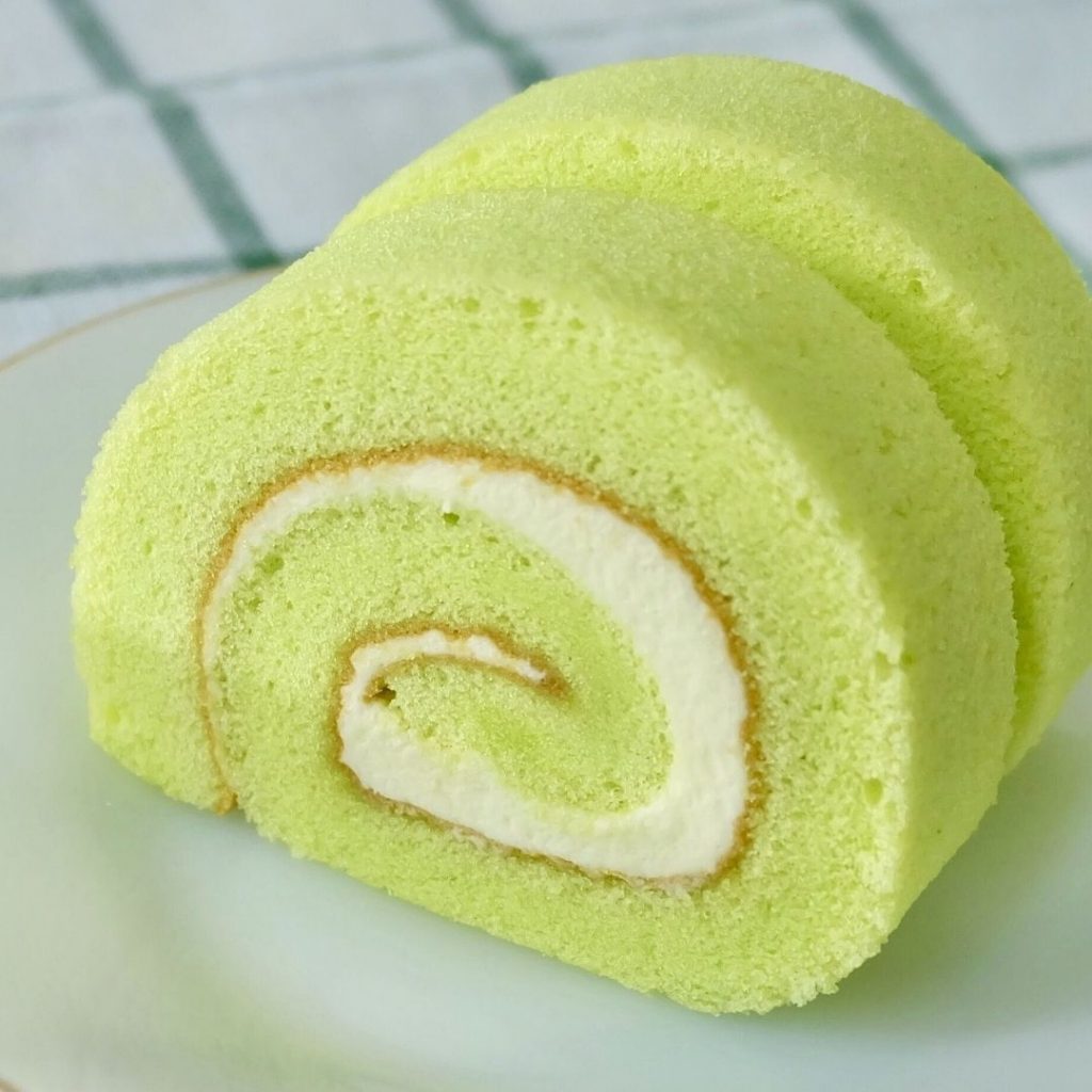 Två bitar av matcha swiss roll fylld med fluffig grädde och rullad till perfektion