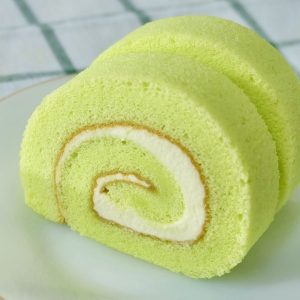 Två bitar av matcha swiss roll fylld med fluffig grädde och rullad till perfektion