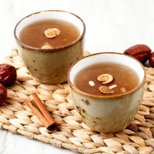 Två koppar med sujeonggwa, koreansk kaneldryck toppad med pinjenötter och torkad jujube
