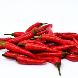 En bild på en hög med röd chili, fmed sin skinnade röda färg, för kryddning och hetta i matlagning.