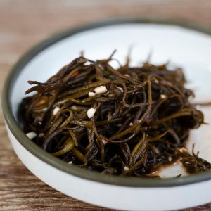 En bild på gosari namul, en koreansk rätt med sautéade ormbunksstjälkar, serverade på ett litet fat.