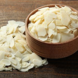 En liten skål med mandelspån och spridda på ett träbord, perfekta för bakning och matlagning