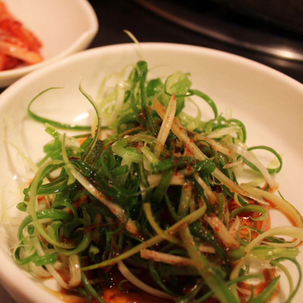 En liten tallrik med pa-muchim, strimlad salladslök blandad med kryddor, populär koreansk sallad till grillat kött