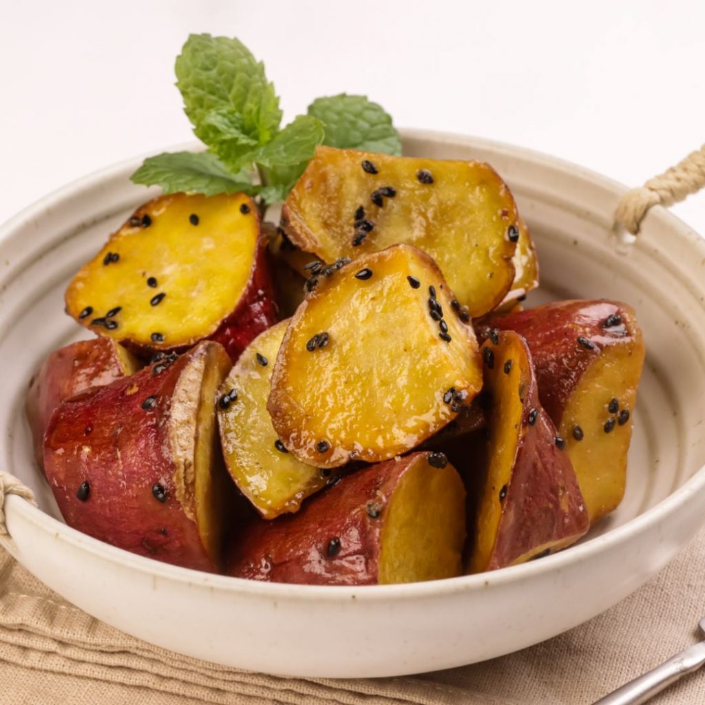 En skål med Goguma mattang, karamelliserade sötpotatisbitar med en glansig honungsglasyr