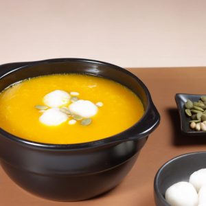 En skål med Hobakjuk, en len och söt gulorange gröt gjord på kabocha pumpa med risbollar