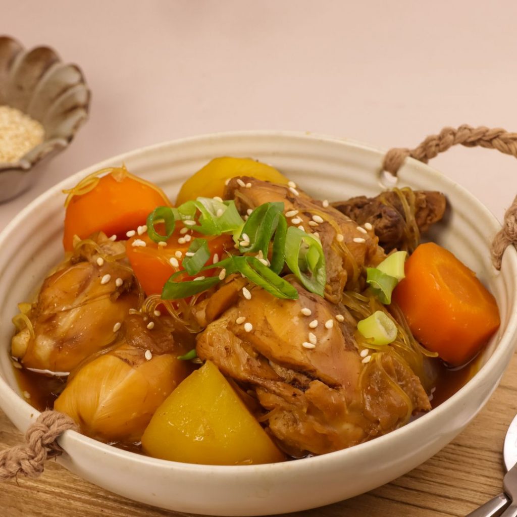 En skål med Jjimdak, smakrik koreansk kycklinggryta med sojasås, nudlar och grönsaker