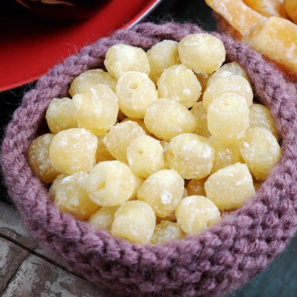 En stickad skål med Kanderade lotusfrön, söta och glaserade för en perfekt festlig snack