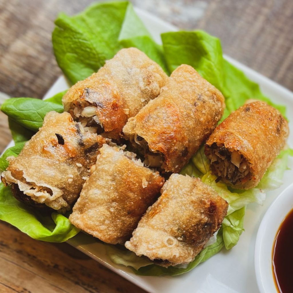 En tallrik med Krispiga vårrullar fyllda med färska grönsaker och kryddor på salladsblad.