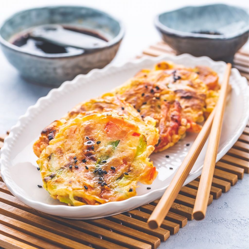 En tallrik med Yachaejeon, koreanska grönsakspannkakor, gyllenbruna och krispiga, serverade som en lätt förrätt