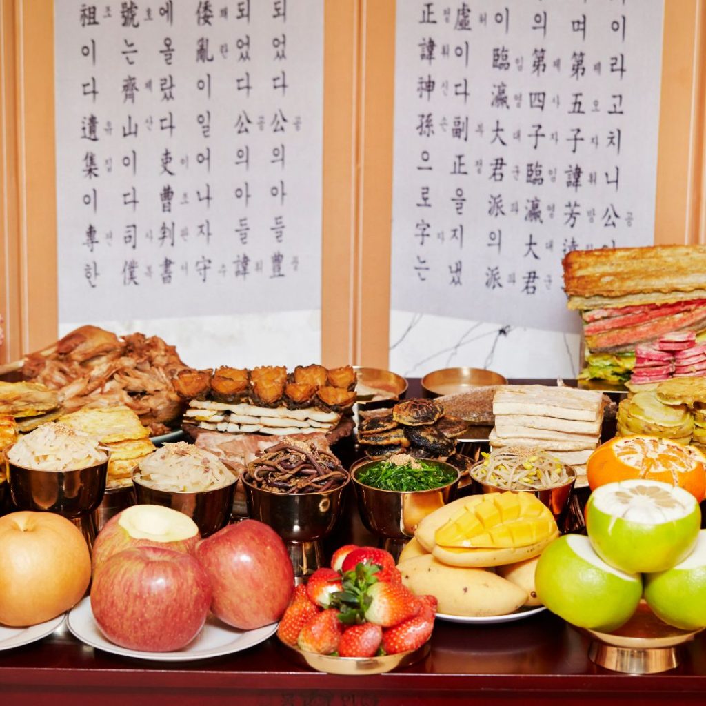 Ett koreanskt förfäders ceremoni-bord dekorerat med tteok, frukt, banchan och traditionella drycker för minneshögtiden