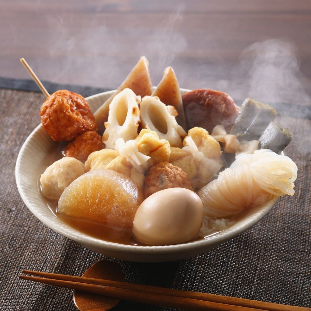 En skål med japansk oden, fylld med olika ingredienser som daikon, ägg och fiskkakor i en smakrik dashi-buljong.