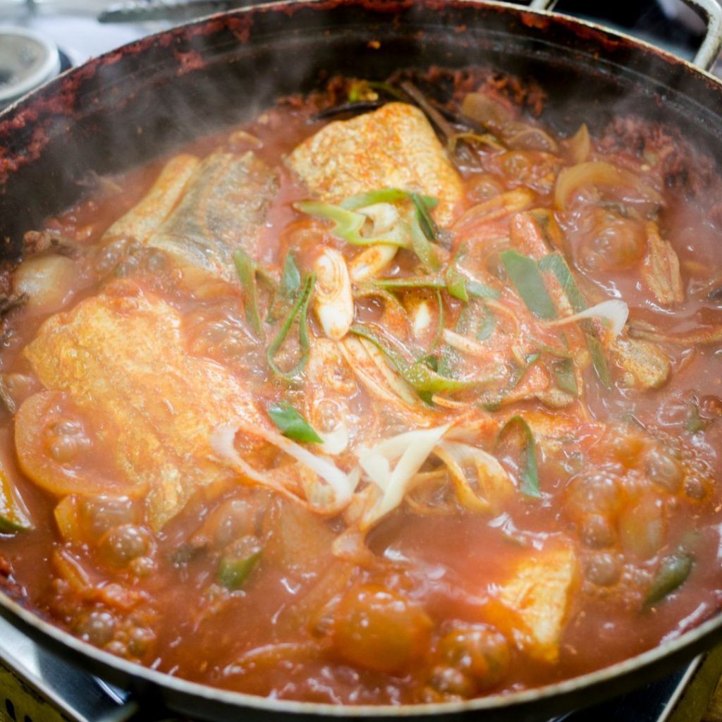 En skål med koreansk maeuntang, en het och kryddig fisksoppa med grönsaker och tofu i en mustig buljong.