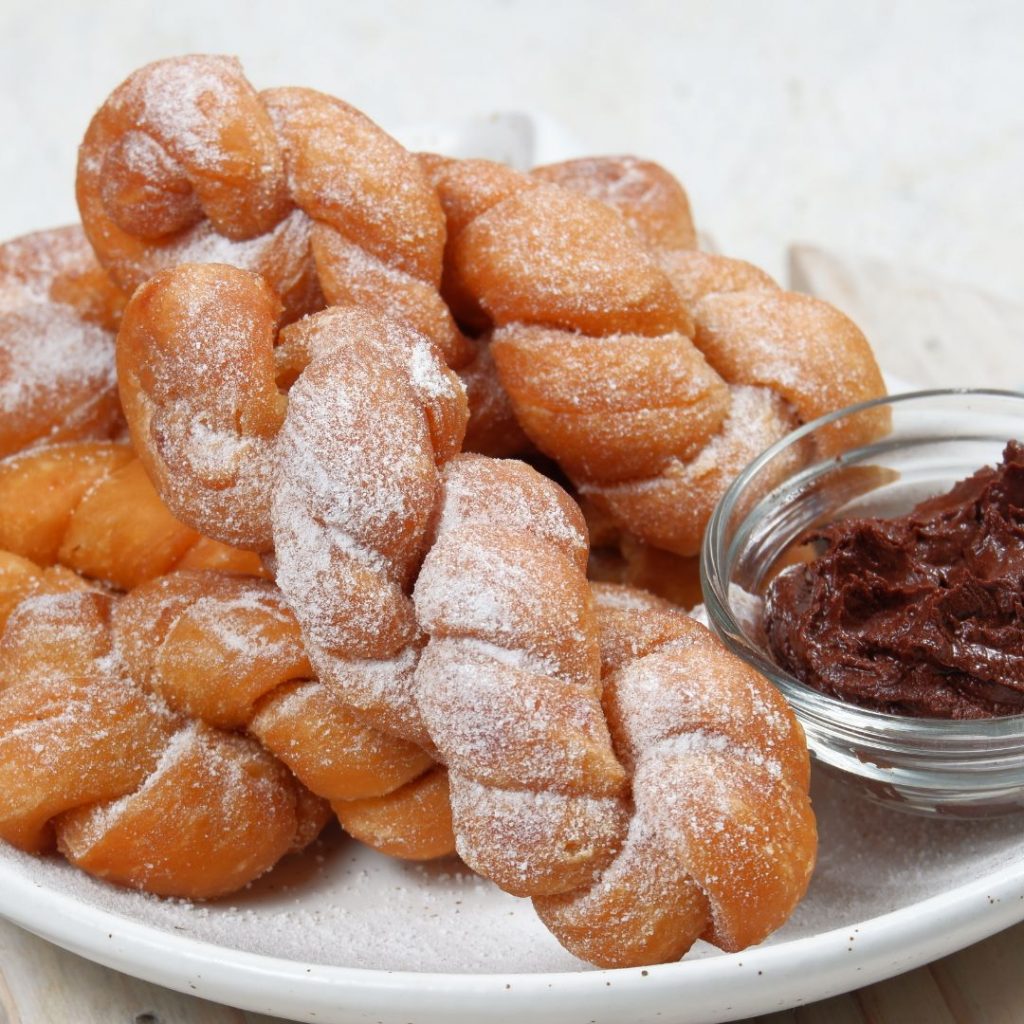 En tallrik med koreanska kkwabaegi, mjuka och fluffiga friterade munkar med en söt kanelsockerbeläggning