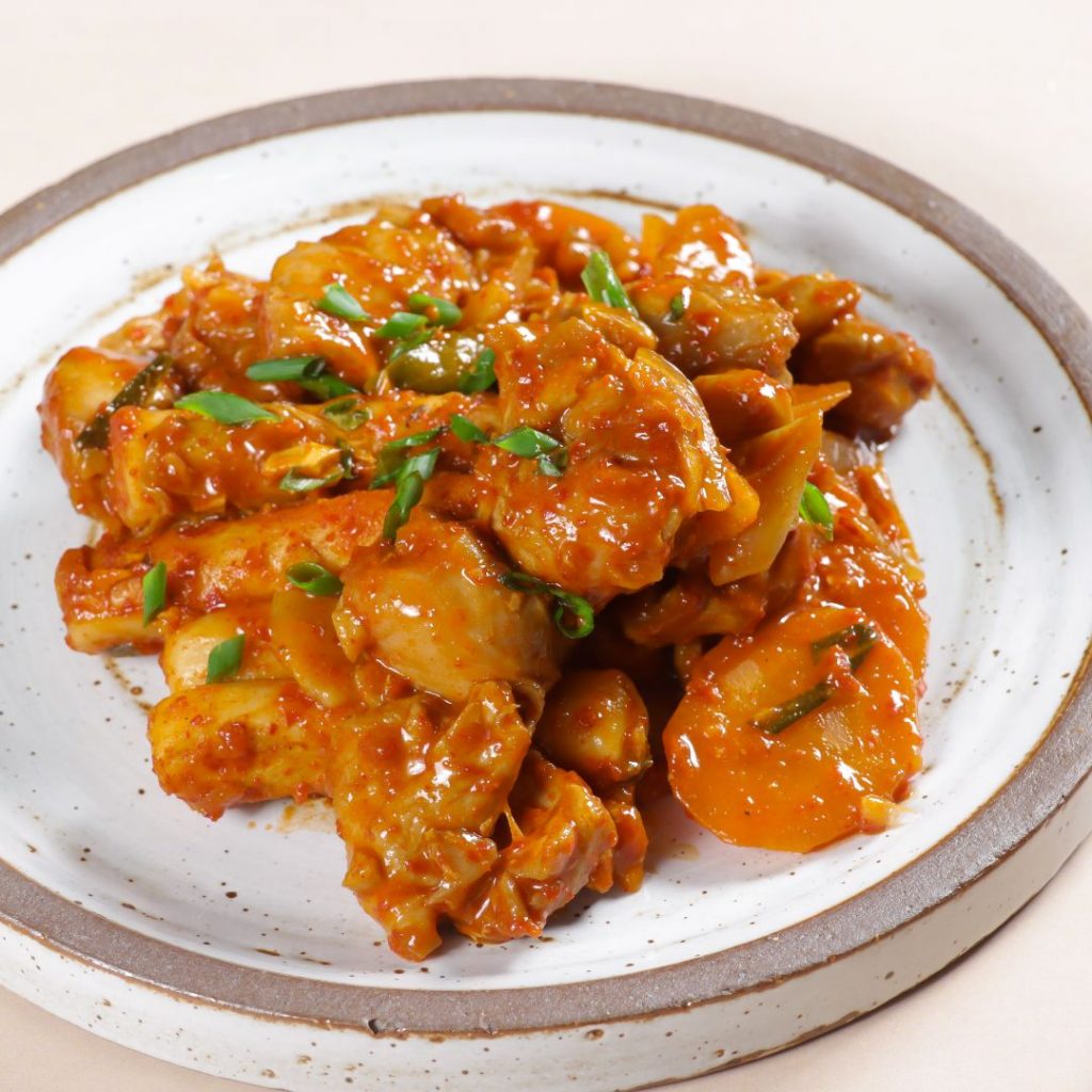 En tallrik med med kryddig koreansk dakgalbi, stekt kyckling med grönsaker och gochujang, serverad med ris eller ost