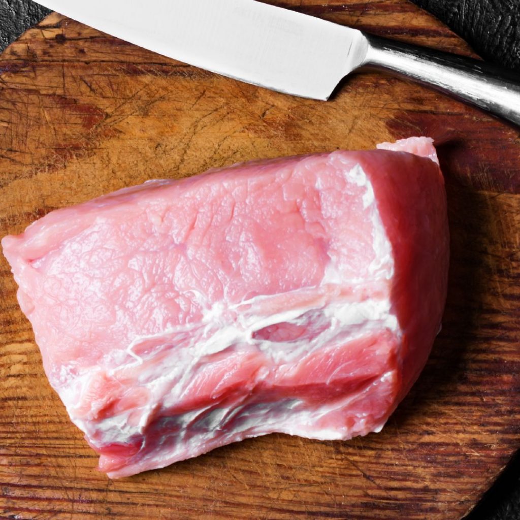 En skärbräda med rå fläskkött i bit, en ingrediens som används i många rätter som grytor, wokar och grillade maträtter.