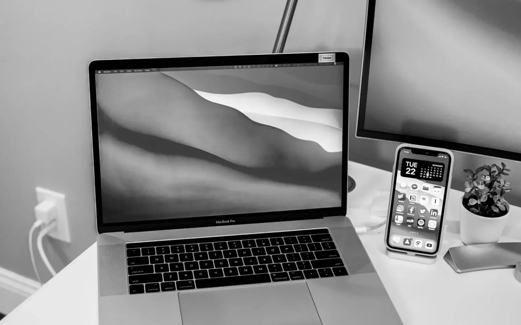 Laptop und Smartphone stehen auf einem Schreibtisch, schwarz-weiss