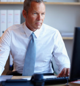 Serious mature business man working on a project using computer