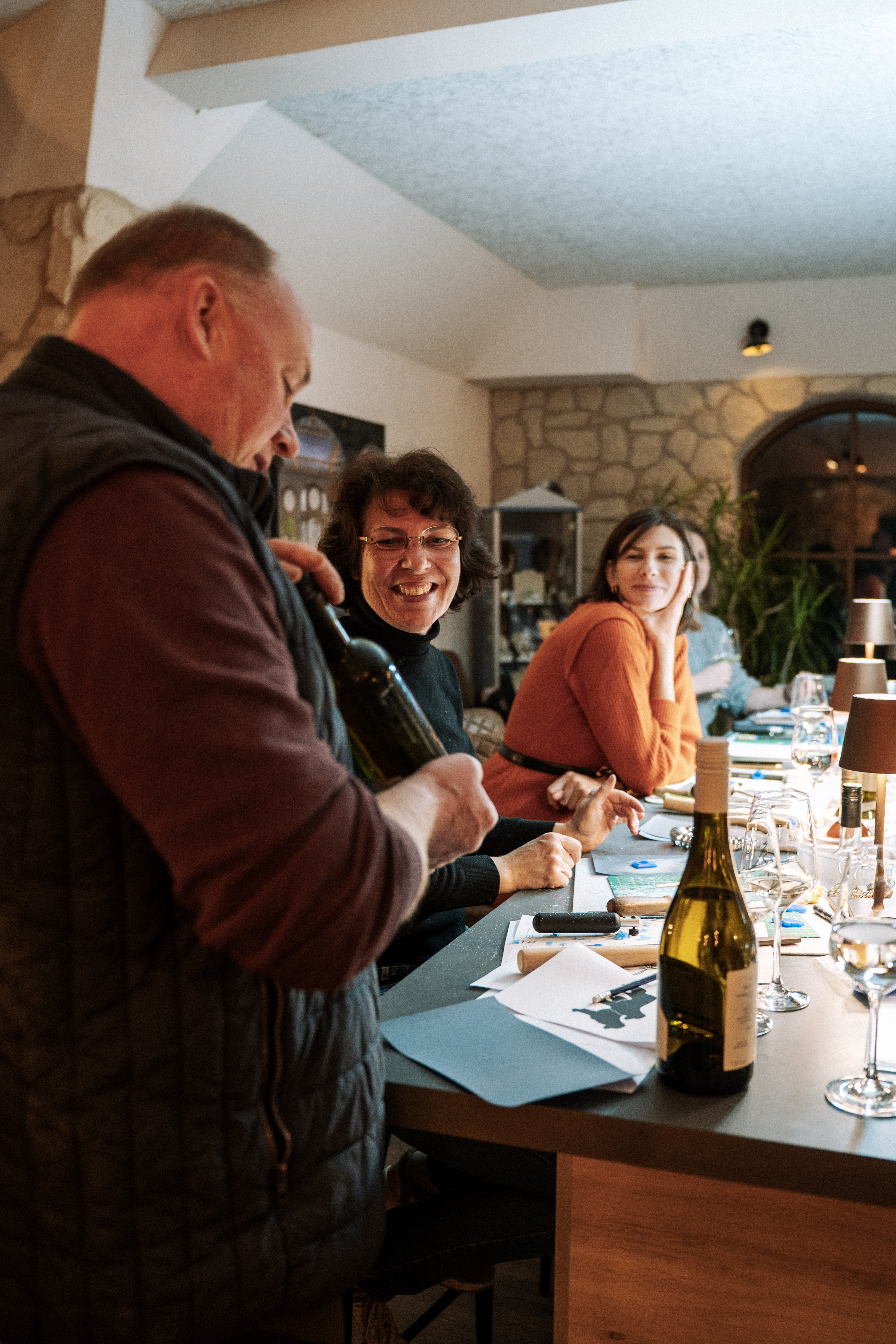 Christian schenkt Wein bei einer Weinprobe im Weingut Buchenländerhof aus, Gäste sitzen am Verkostungstisch.