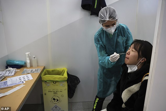 Pictured: A passenger arriving from China is tested for Covid at the Roissy Charles de Gaulle airport in Paris, France, on Sunday