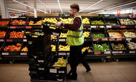 A picture of an employee arranging produce inside a Sainsbury’s supermarket in Richmond, west London.