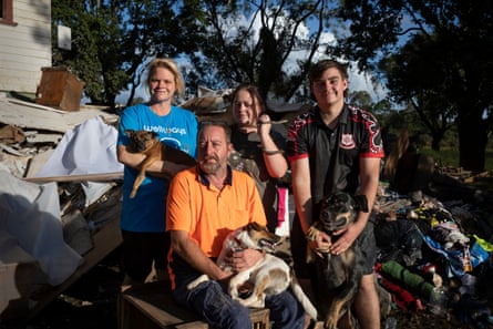 (L-R) Primrose Trew holds Dixie, Chris Trew holds Spud, Daizie Trew holds Biscuit the python, and Maxx Trew holds Cole in front of their home in Lismore that was hit by destroyed flooding in February 2022.