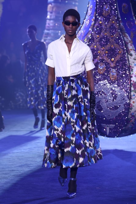 Model on the catwalk wearing white collared shirt, blue printed New Look-style skirt, black opera gloves.