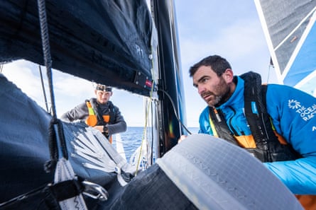 Charlie Enright and Jack Bouttell assess the tear in the mainsail before starting repairs.