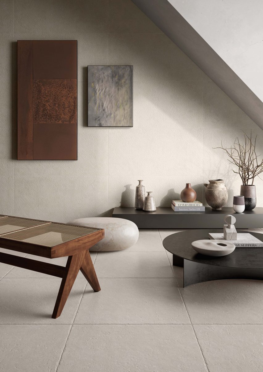 Corner of room with pale tiles on floor and walls and low, modern tables