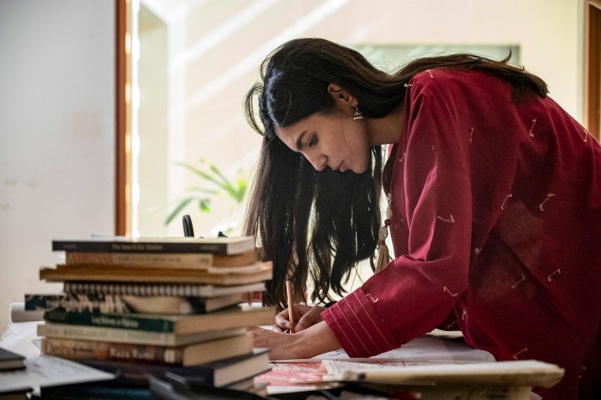 Woman in red shirt bent over a drawing table