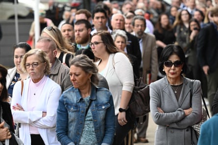 Reporters and members of the public line up to enter the court for the trial.