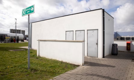 A bare, plain white toilet block in a car park