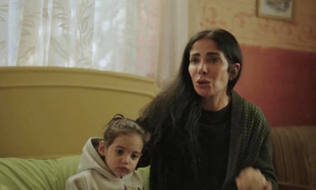 A still from TV showing a woman sitting on a sofa with a young child