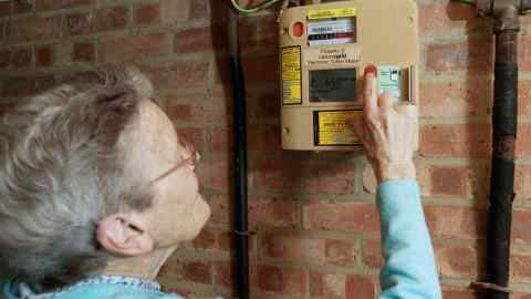 An elderly woman using a quantum key prepayment gas meter to check the amount of credit remaining