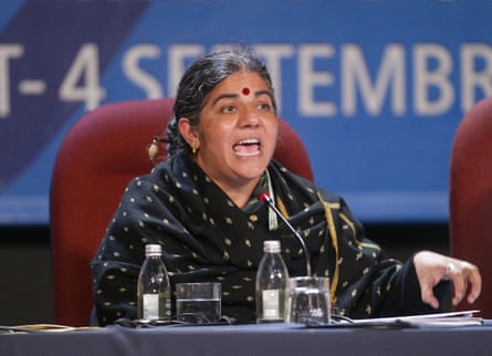 An Indian woman in a sari speaking from a stage