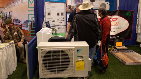 Potential customers chat with a heat pump vendor at the Green Home + Energy Show in South Portland.