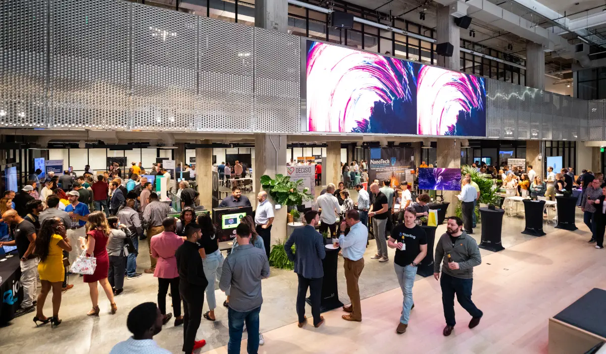 A bustling floor with people gathered at booths and talking in small groups in Houston's Ion building