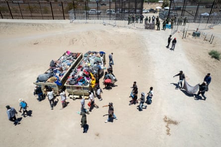 In an aerial view, migrants sort used clothing and blankets into dumpsters before being processed to make asylum claims at a makeshift migrant camp on 11 May in El Paso, Texas.