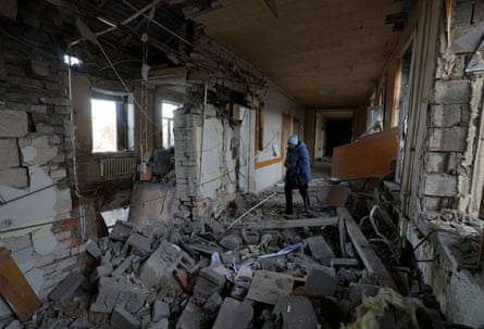 A woman walks through the rubble of a ruined building