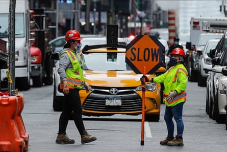 construction workers hold sign that says 'slow' on street