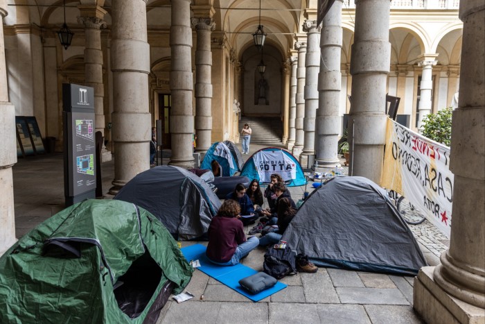 Student sitting in front of tents and banners