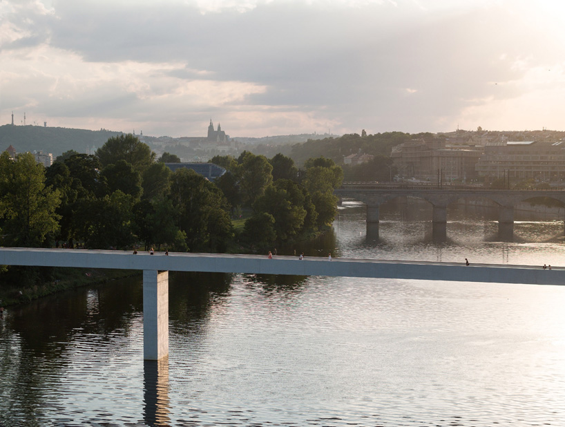 sleek concrete pedestrian bridge spans the vltava river in prague